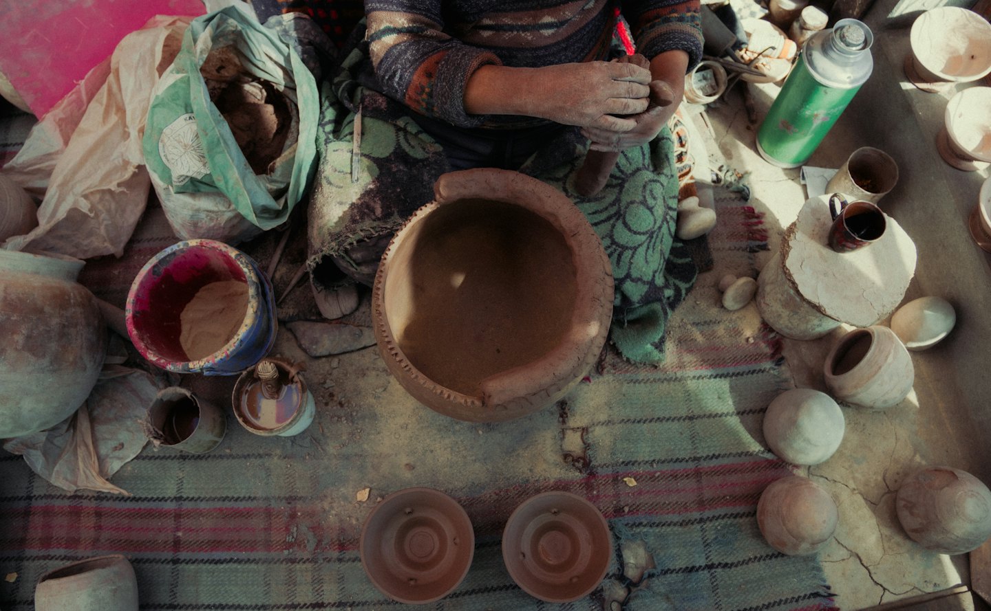 An artisan carves a clay pot in a pottery studio.