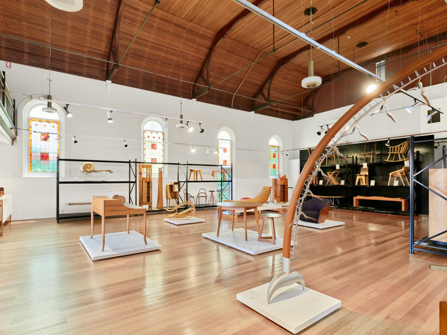 Wooden furniture pieces displayed inside a modern gallery space.